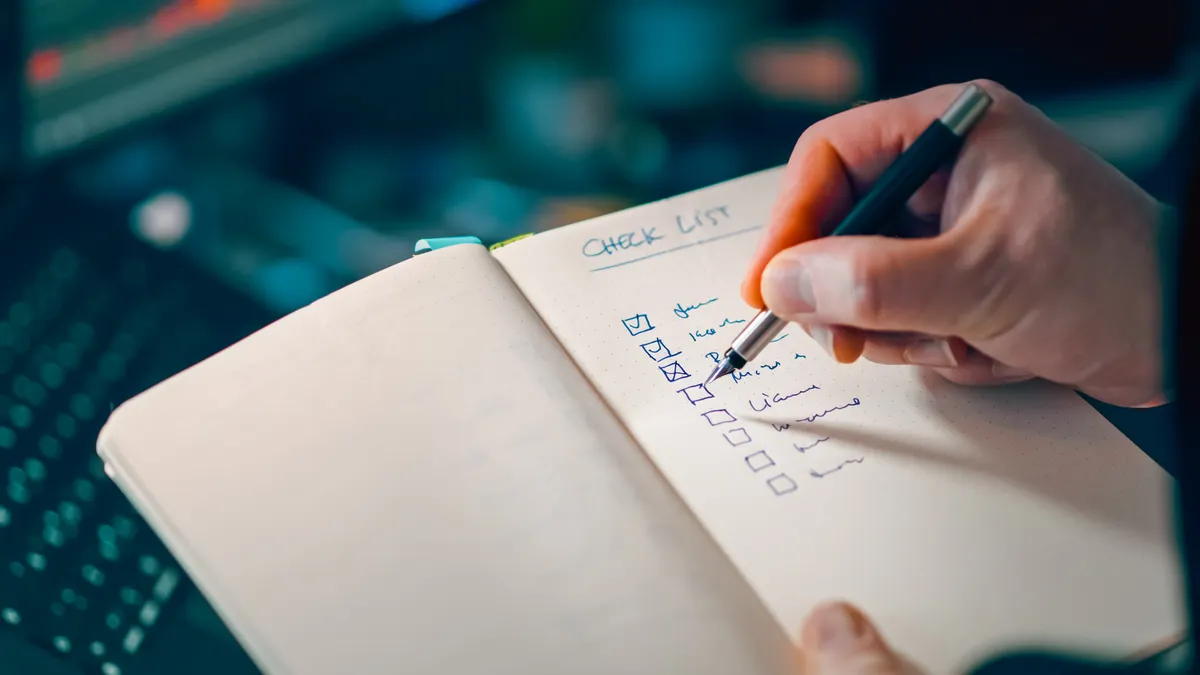 Hand ticking off checklist items in a notebook
