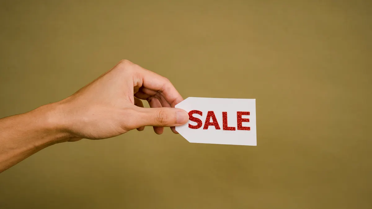 Sell a website privately: how to find, vet and close deals off-market — Crop faceless person demonstrating sign Sale